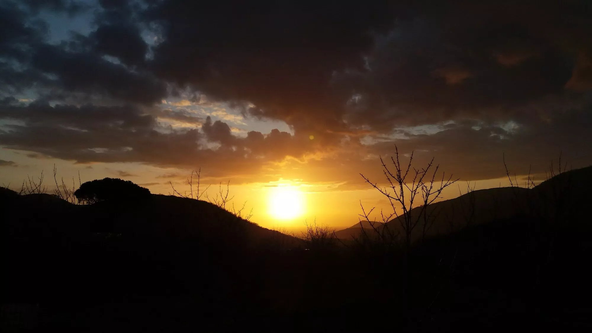 Il sole che tramonta dietro le colline